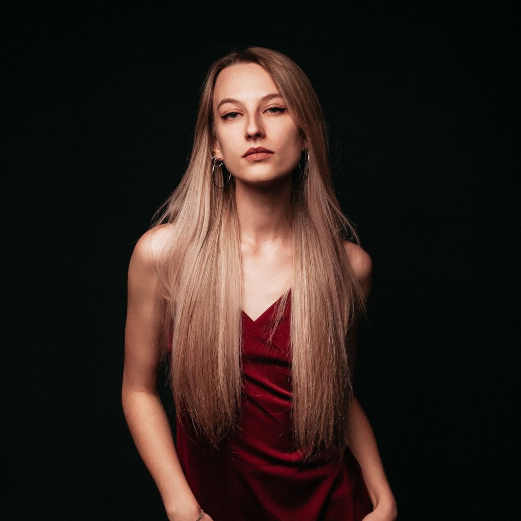 Elegancki portret kobiety w czerwonej sukience na ciemnym tle, ucieleśniający elegancję